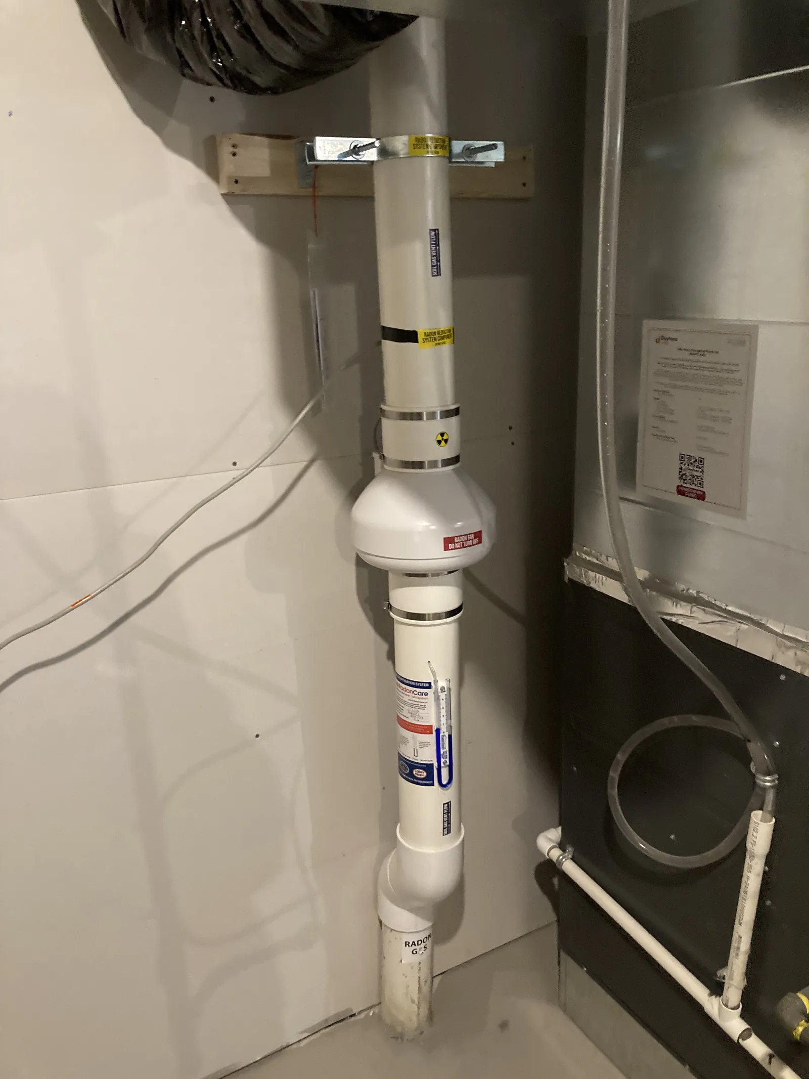 Radon Fan And Labelled Pipe Beside The Furnace In The Mechanical Room Of A New Cochrane Home