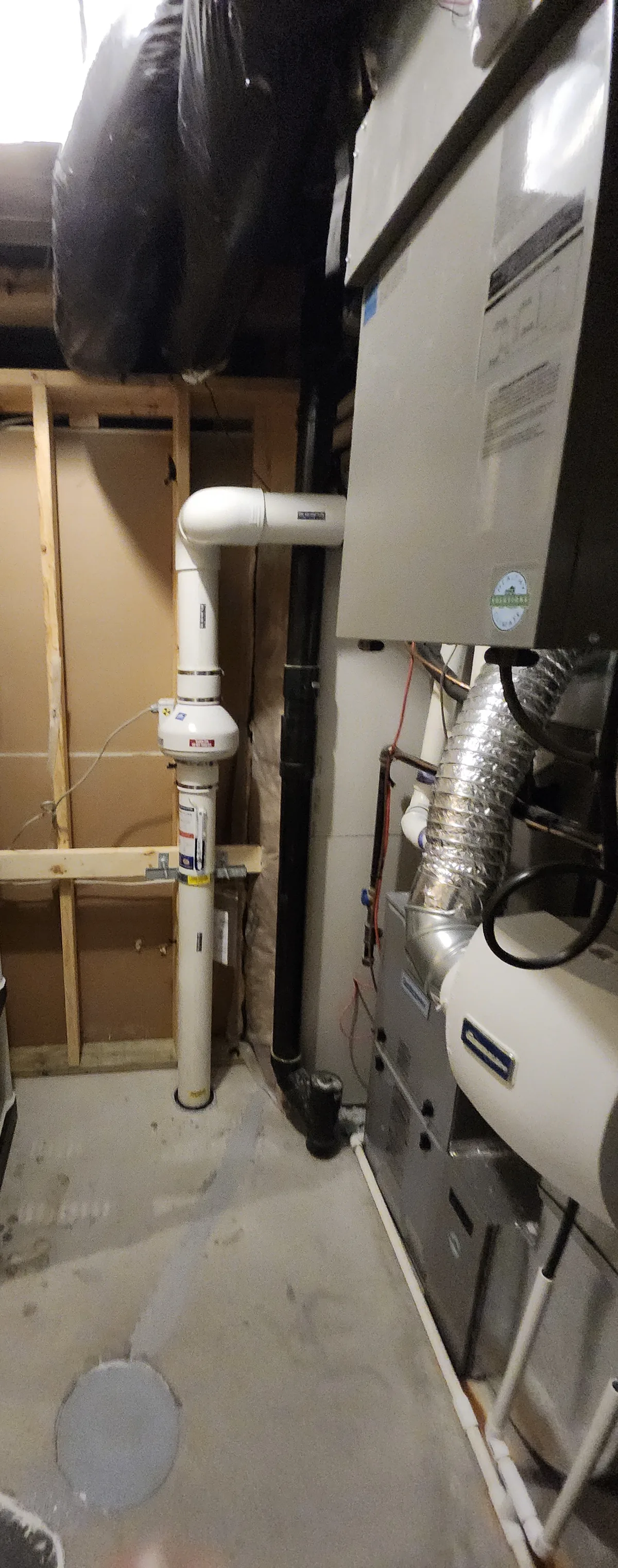 A Radon Fan And Labelled Pipe On A Framed Wall Beside The Furnace And Water Heater In An Okotoks Mechanical Room