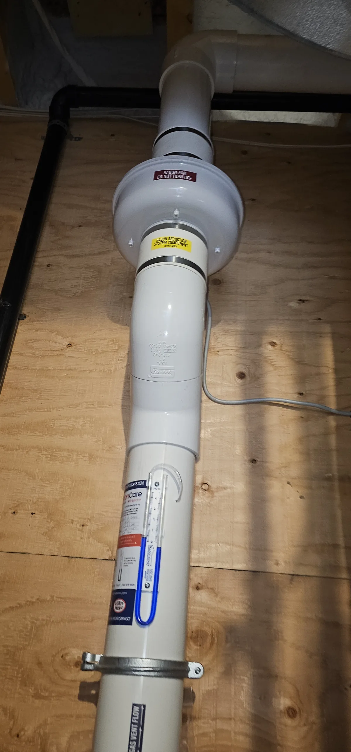 Radon Fan And Pressure Gauge In A Plywood Utility Closet In A Priddis Home