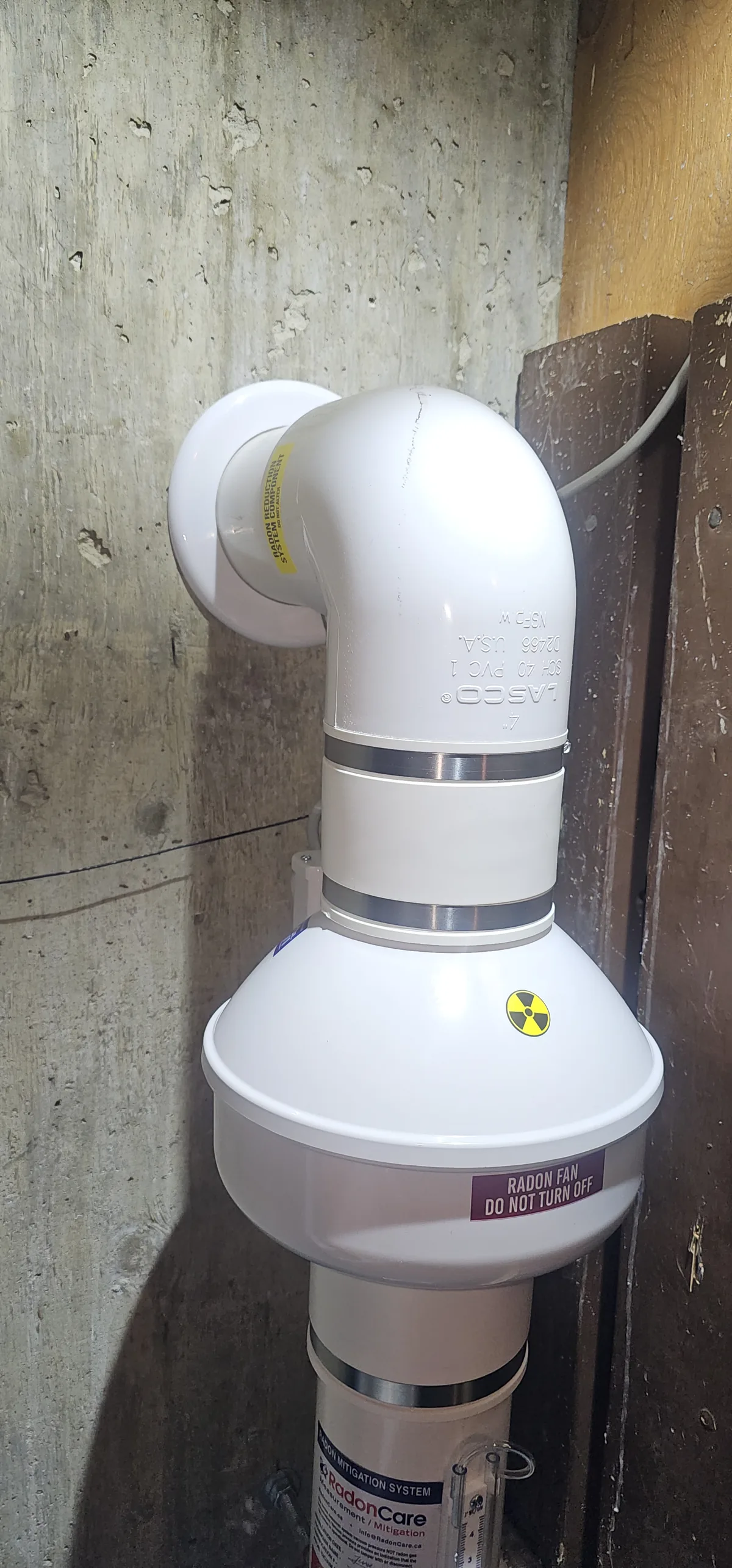 A Radon Fan And Labelled Pipe On A Concrete Basement Wall In A St. Albert Home