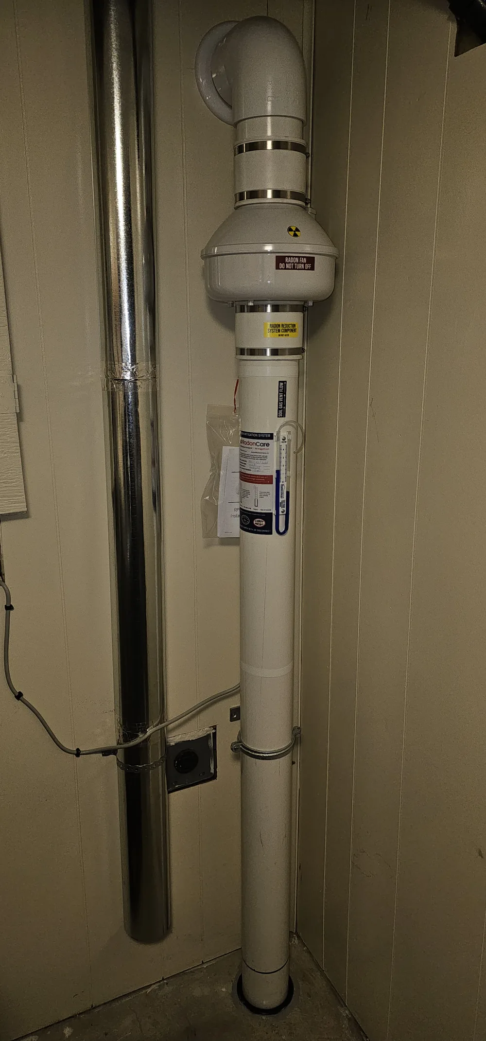Radon Fan And Pipe In A Narrow Utility Closet In A Lacombe Home