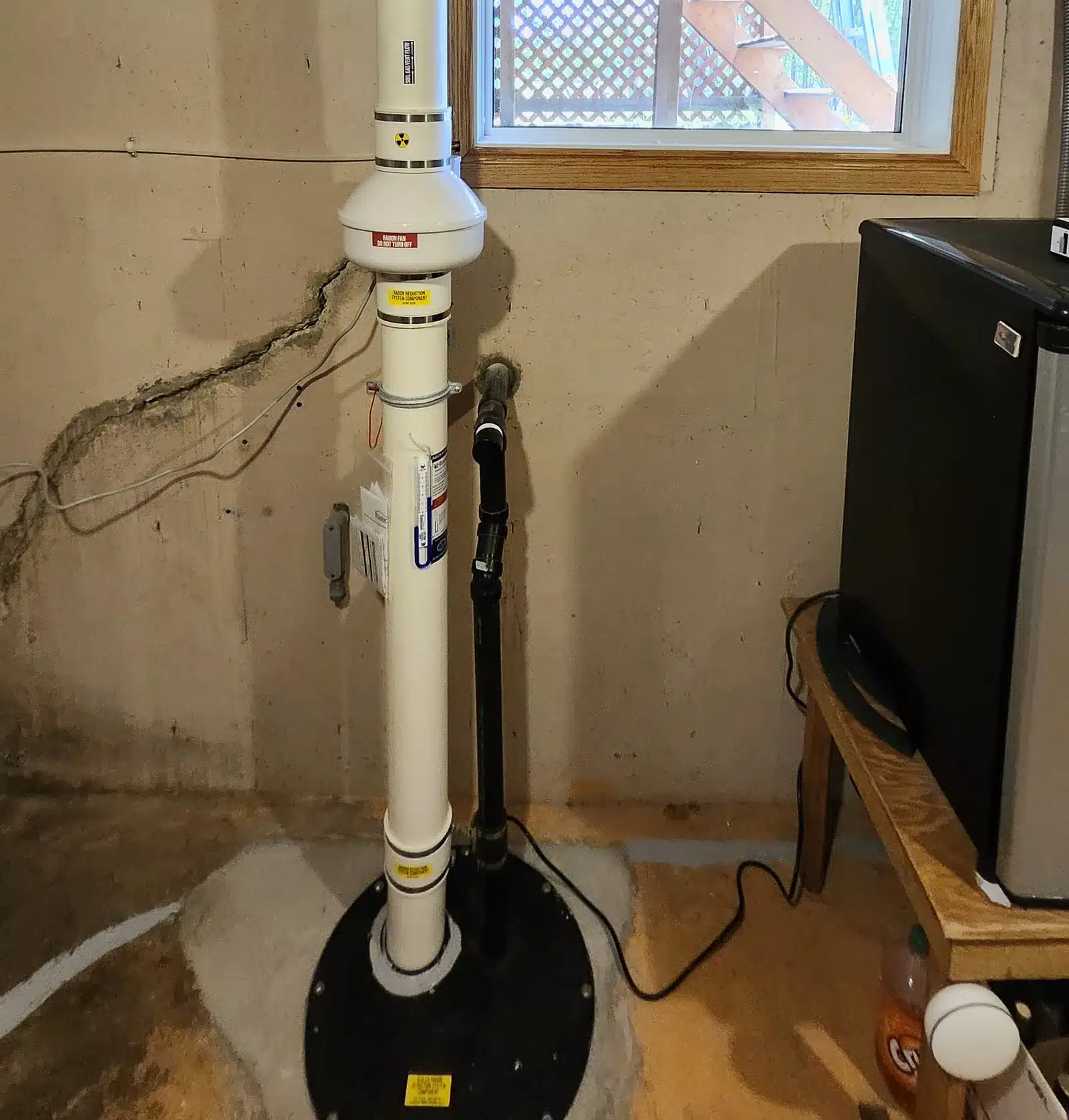 A Radon Pipe And Fan Rising From A Sealed Sump Lid Beside A Basement Window In A Leduc County Acreage Home