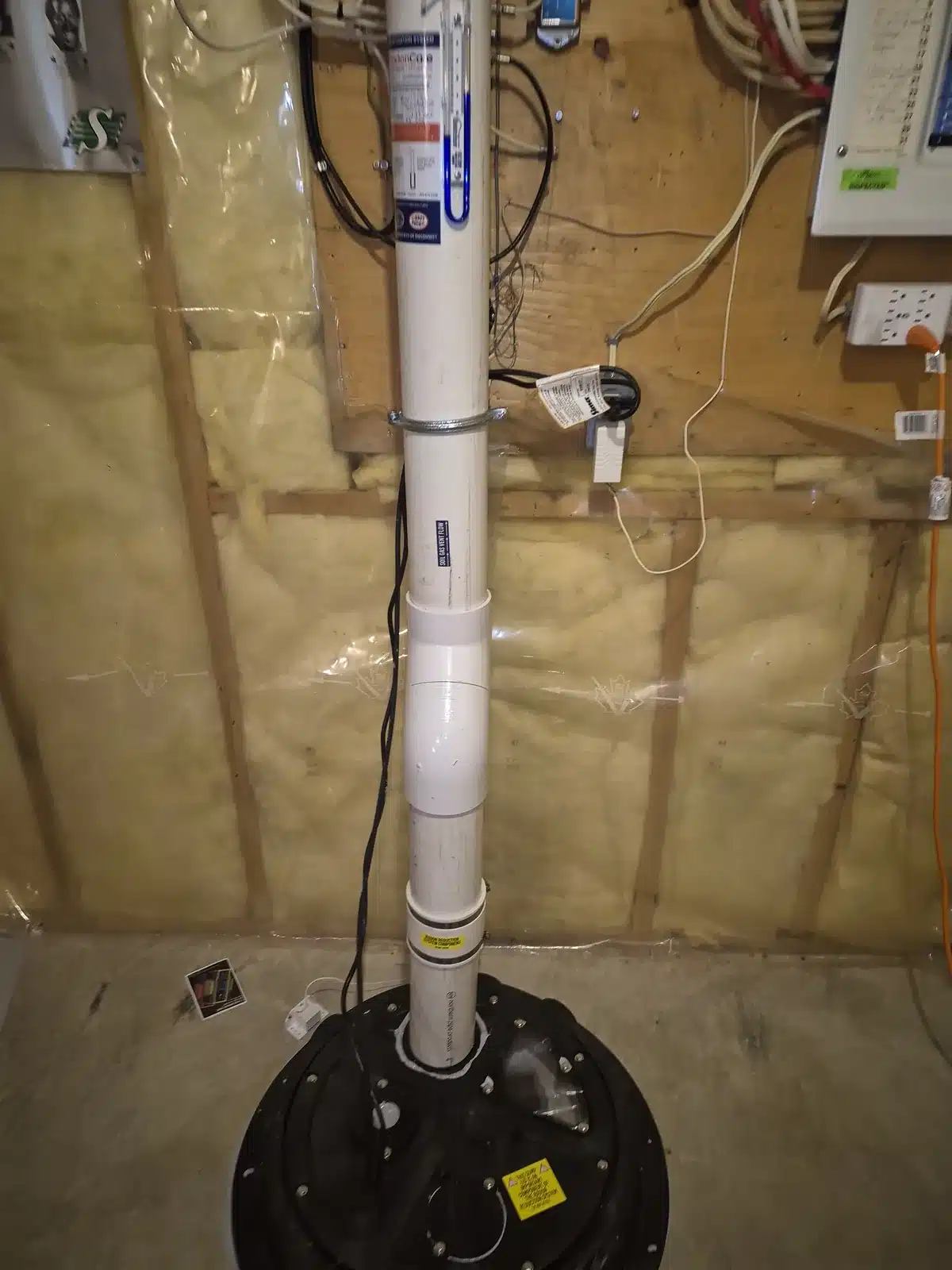 Radon Pipe Rising From A Sealed Sump Lid Along An Insulated Basement Wall In A St. Albert Home